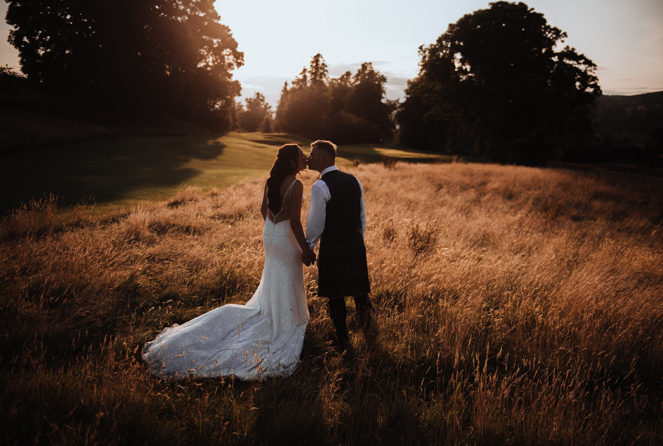 Wedding couple kiss in the grass field