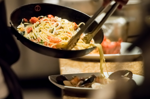 Chef dishing up seafood linguine with mussels, cherry tomatoes, and fresh herbs at Il Posto, an Italian pizza and pasta restaurant in Bishopton near Glasgow